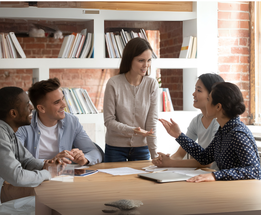 A group of colleagues discussing a matter around a table with someone leading the discussion.